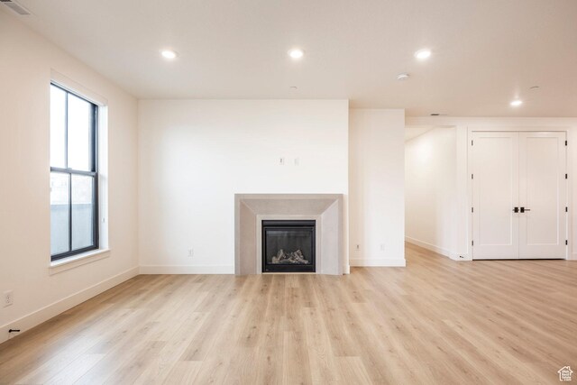 2250 E Murray Holladay Rd Unit 205, Holladay, UT 84117 - unfurnished living room with light wood finished floors, recessed lighting, visible vents, and a glass covered fireplace