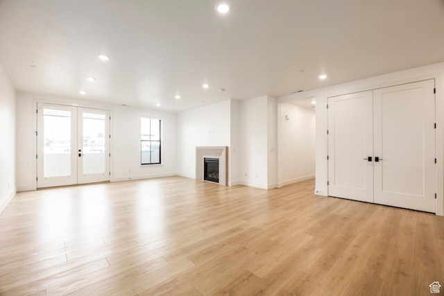 2250 E Murray Holladay Rd Unit 205, Holladay, UT 84117 - unfurnished living room with light wood finished floors, recessed lighting, french doors, and a glass covered fireplace