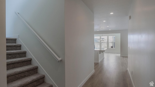 stairway featuring baseboards, recessed lighting, wood finished floors, and a textured ceiling