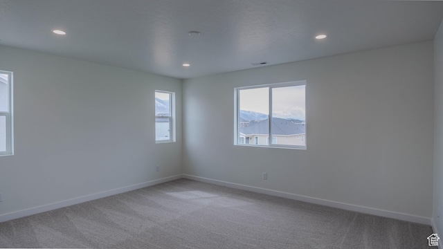 spare room with visible vents, baseboards, recessed lighting, and light colored carpet