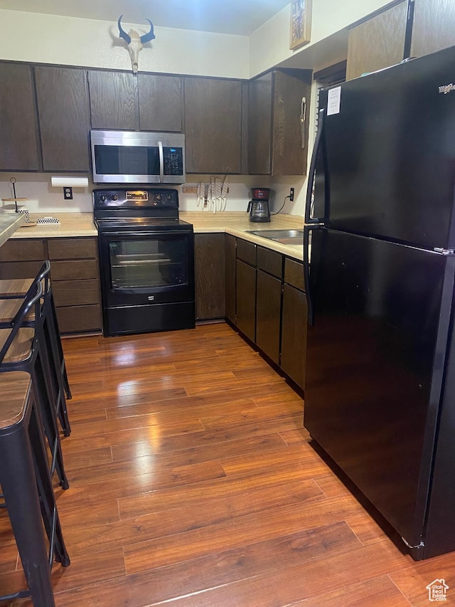 5980 S 9000 E, Jensen, UT 84035 - kitchen featuring wood finished floors, black appliances, dark brown cabinets, and light countertops