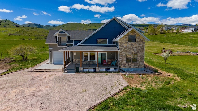 1595 S Bear Lake Blvd, Garden City, UT 84028 - view of front of house with a mountain view, covered porch, stone siding, concrete driveway, and a front yard
