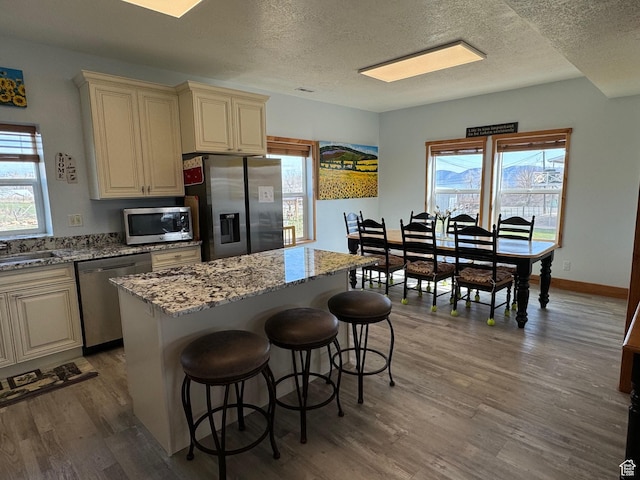1595 S Bear Lake Blvd, Garden City, UT 84028 - kitchen with light stone counters, a breakfast bar area, stainless steel appliances, a kitchen island, and wood finished floors