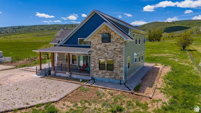 1595 S Bear Lake Blvd, Garden City, UT 84028 - back of house with covered porch, stone siding, a lawn, and a mountain view