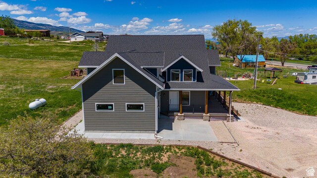 1595 S Bear Lake Blvd, Garden City, UT 84028 - view of front of house featuring a front lawn, a mountain view, a porch, and roof with shingles