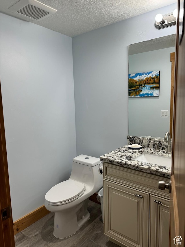 1595 S Bear Lake Blvd, Garden City, UT 84028 - half bathroom featuring visible vents, toilet, vanity, a textured ceiling, and wood finished floors