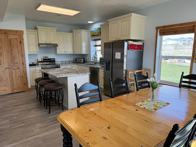 1595 S Bear Lake Blvd, Garden City, UT 84028 - kitchen with a center island, cream cabinetry, stainless steel appliances, a sink, and under cabinet range hood