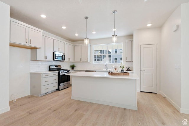 10053 N Torreya Dr Unit 733, Highland, UT 84003 - kitchen with stainless steel appliances, a kitchen island, light wood-style floors, light countertops, and pendant lighting