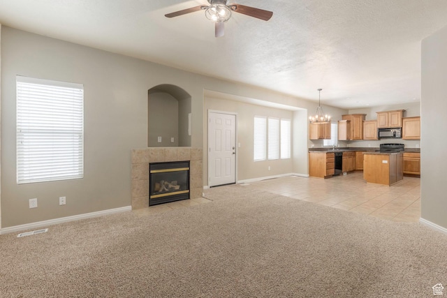 898 E Tendoy Ct S, Draper, UT 84020 - unfurnished living room with visible vents, baseboards, ceiling fan with notable chandelier, light colored carpet, and a tile fireplace