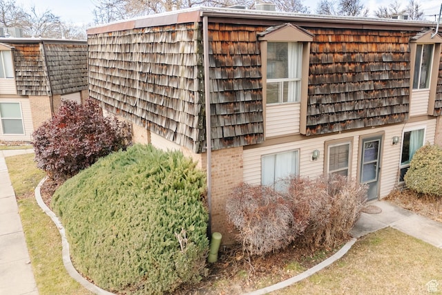 view of side of property featuring mansard roof and brick siding