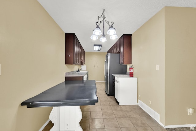 kitchen featuring a sink, visible vents, baseboards, a chandelier, and light tile patterned floors