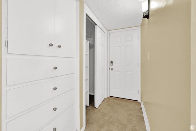 hall with baseboards and a textured ceiling