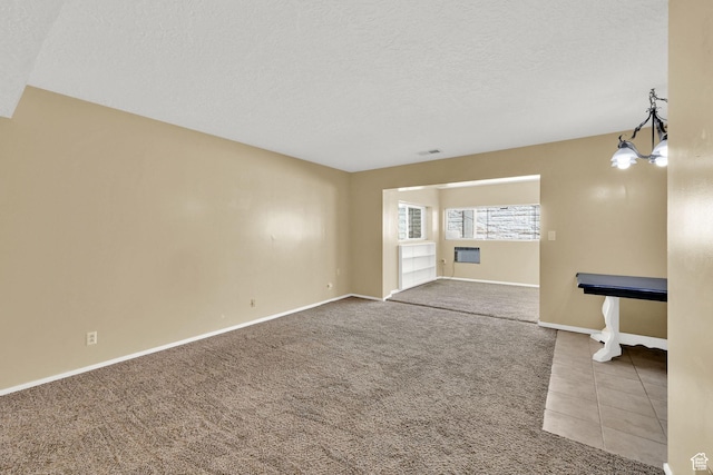 unfurnished living room with carpet, visible vents, baseboards, a chandelier, and a textured ceiling