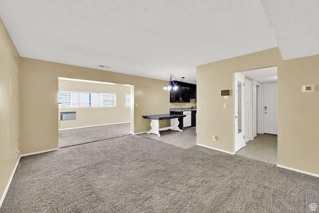 unfurnished living room featuring light colored carpet, baseboards, a textured ceiling, and visible vents