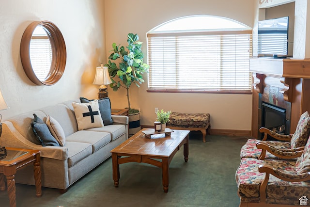 living room with dark carpet, a fireplace, and baseboards