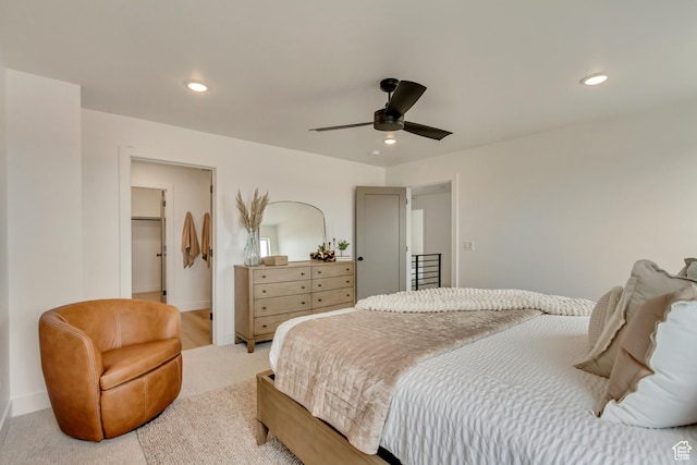 bedroom featuring light carpet, baseboards, recessed lighting, and a walk in closet