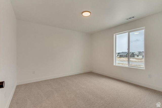 empty room with light carpet, visible vents, and baseboards