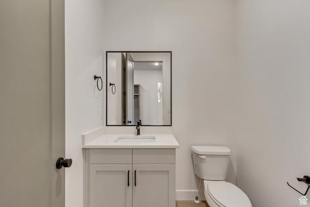 half bathroom with toilet, vanity, and baseboards