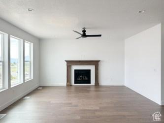 5644 W 7340 S, West Jordan, UT 84081 - unfurnished living room featuring a ceiling fan, wood finished floors, baseboards, and a fireplace