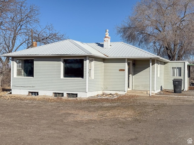 view of front facade with metal roof and a chimney