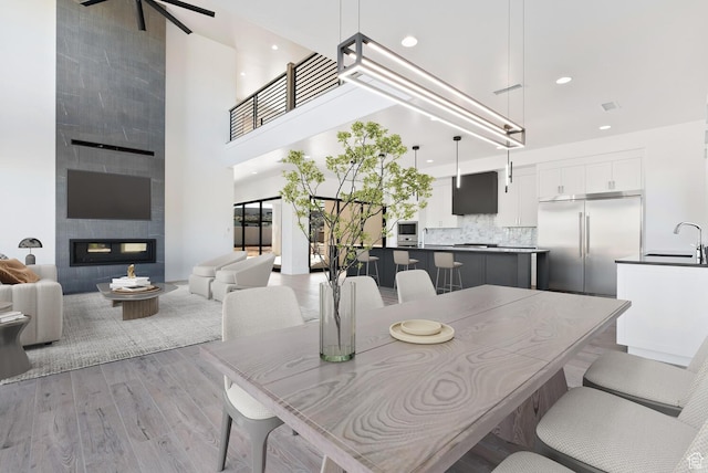 1461 W Canyon Tree Dr, St George, UT 84770 - dining area featuring a tile fireplace, light wood-style flooring, a towering ceiling, and recessed lighting