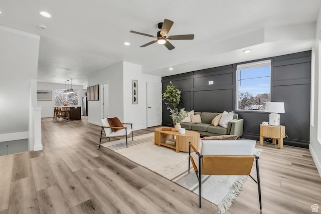 239 E Burch Creek Pl S, Ogden, UT 84405 - living room with light wood finished floors, a healthy amount of sunlight, a ceiling fan, and a decorative wall