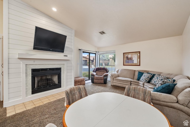 carpeted living room featuring vaulted ceiling, a fireplace, visible vents, and tile patterned floors