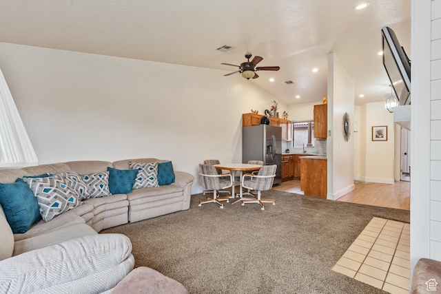 living room featuring lofted ceiling, visible vents, light carpet, ceiling fan, and light tile patterned flooring