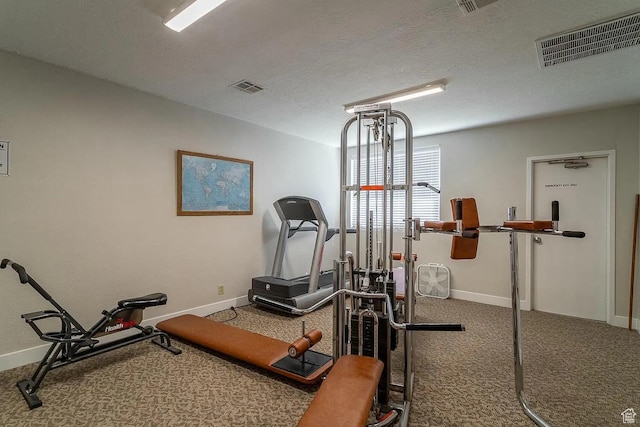 exercise area featuring carpet floors, baseboards, visible vents, and a textured ceiling