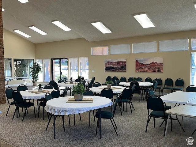 dining room with a textured ceiling, high vaulted ceiling, and light colored carpet