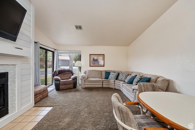 living area featuring light tile patterned floors, visible vents, light colored carpet, lofted ceiling, and a fireplace