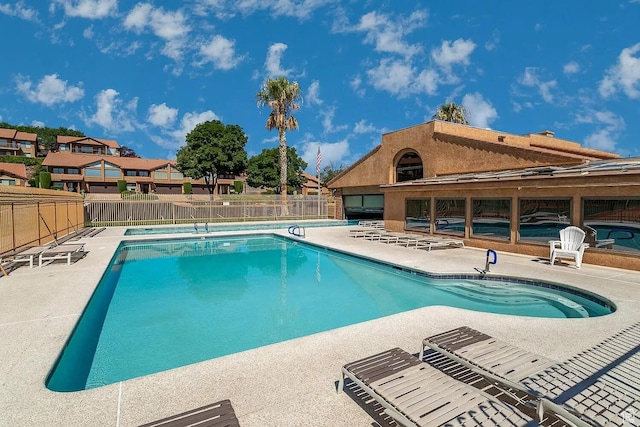 community pool with a patio area and fence