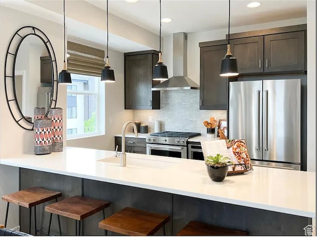 6785 Silver Creek Dr N, Park City, UT 84098 - kitchen with wall chimney exhaust hood, appliances with stainless steel finishes, decorative backsplash, decorative light fixtures, and a kitchen bar