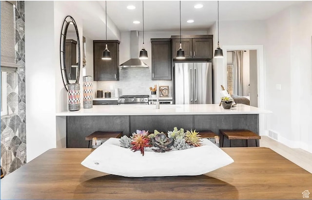 6785 Silver Creek Dr N, Park City, UT 84098 - kitchen featuring stainless steel appliances, wall chimney exhaust hood, dark brown cabinets, decorative backsplash, and a breakfast bar area