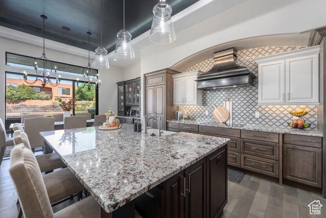 3052 N Snow Canyon Pkwy Unit 201, St George, UT 84770 - kitchen featuring a breakfast bar, a large island, custom range hood, backsplash, and dark brown cabinets