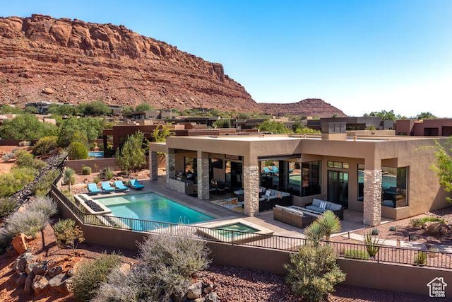 3052 N Snow Canyon Pkwy Unit 201, St George, UT 84770 - rear view of property with a mountain view, an in ground hot tub, stucco siding, an outdoor living space with a fireplace, and a patio area
