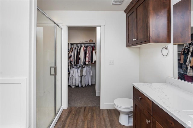 full bath featuring a spacious closet, a stall shower, wood finished floors, and vanity
