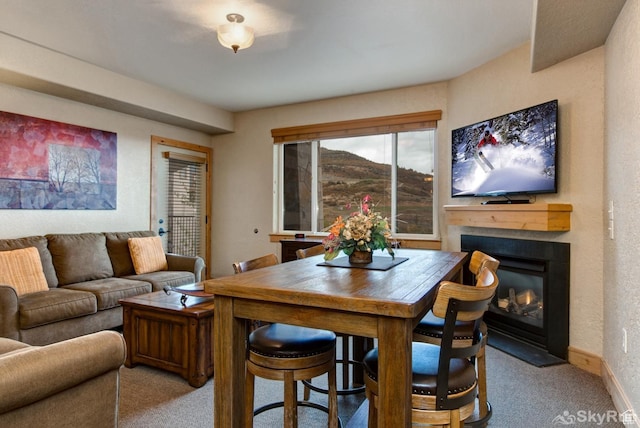carpeted dining room featuring a glass covered fireplace and baseboards