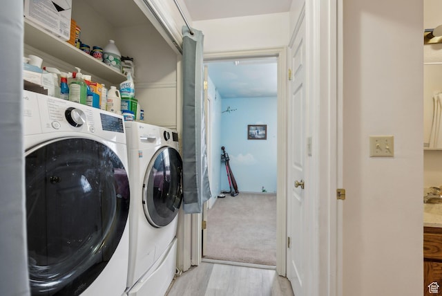 laundry area with washing machine and dryer, light wood-style flooring, and laundry area