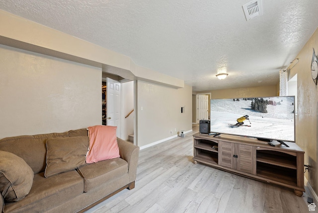 living area with baseboards, a textured ceiling, and light wood-style flooring