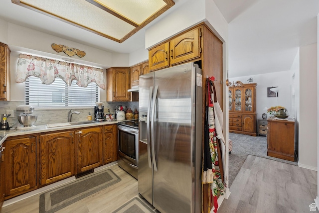 kitchen with stainless steel appliances, brown cabinets, light countertops, and a sink
