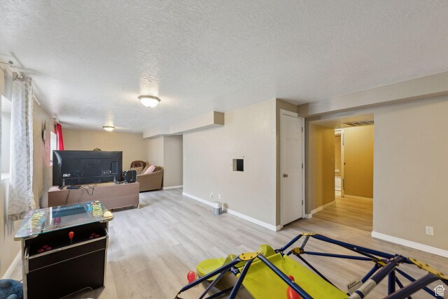 living room featuring a textured ceiling, wood finished floors, visible vents, and baseboards