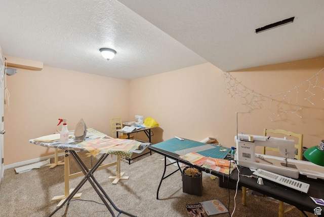 recreation room featuring a textured ceiling and carpet