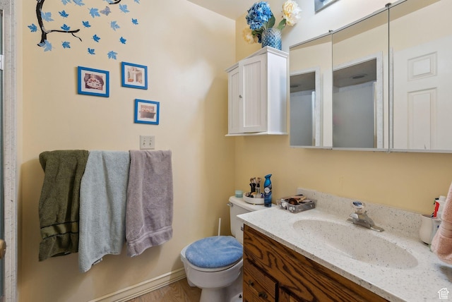 bathroom featuring toilet, wood finished floors, and vanity