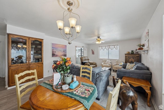 dining room featuring light wood-style flooring and ceiling fan with notable chandelier