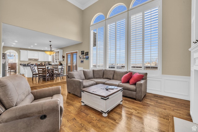 living area with wainscoting, ornamental molding, light wood finished floors, and recessed lighting