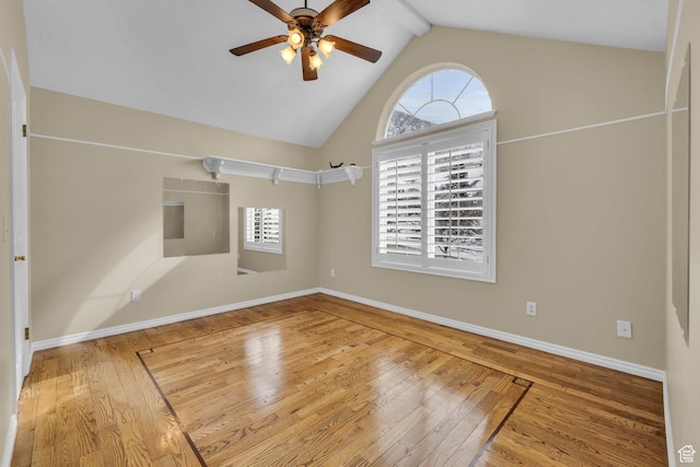 empty room with hardwood / wood-style floors, a wealth of natural light, a ceiling fan, and lofted ceiling with beams