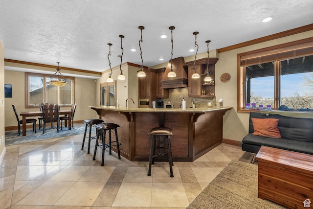 kitchen featuring ornamental molding, baseboards, custom exhaust hood, and a textured ceiling