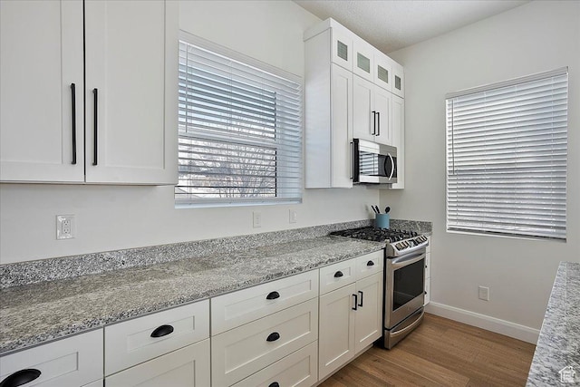 3543 N Creekside Way E Unit 63, Eden, UT 84310 - kitchen featuring light stone counters, light wood finished floors, stainless steel appliances, glass insert cabinets, and white cabinets