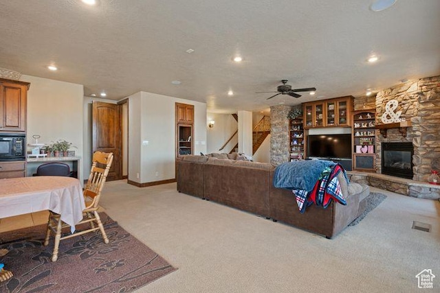 living room featuring a fireplace, recessed lighting, light carpet, a textured ceiling, and baseboards